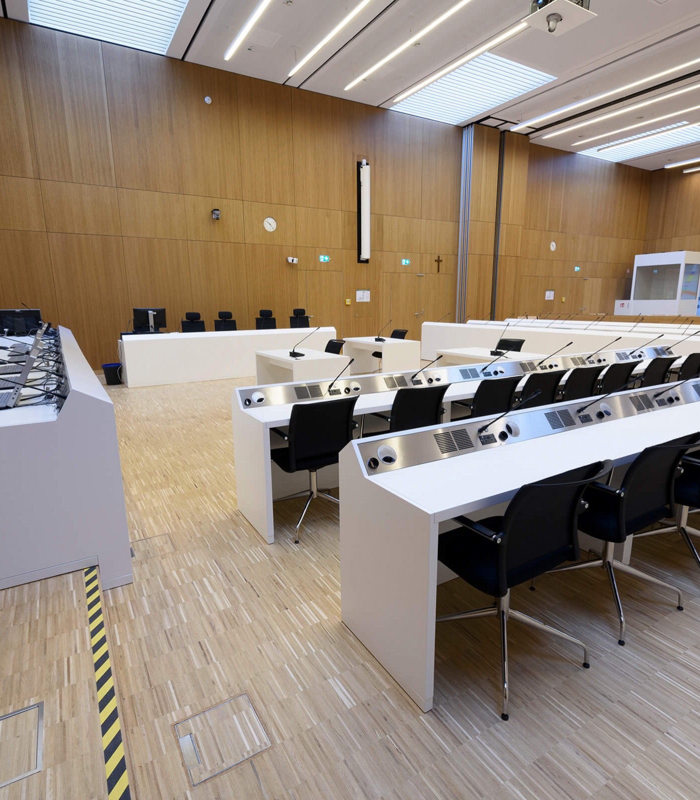 Seitliche Ansicht auf die Anklagebank. Novis Design Monitore FLO erwarten gespannt das Urteil