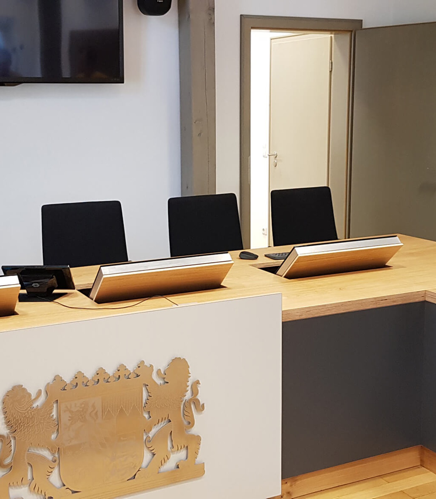 Ansicht von der Saalseite auf die Richterbank, flach verbaut die aufklappbaren Bildschirme